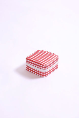 Small square jewelry travel box in maroon gingham pattern with white zipper.