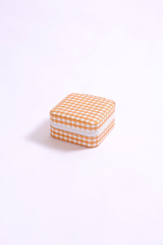 Square gingham print travel jewelry case in bright orange with zipper closure.