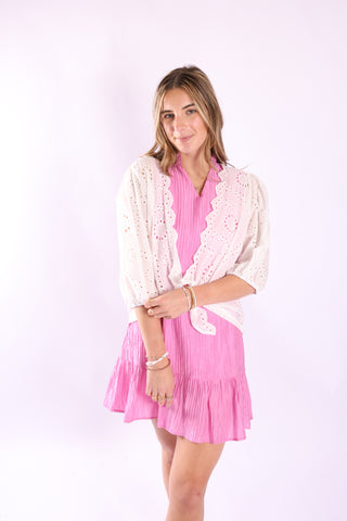 Woman wearing Eyelet Wrap – Spring 2026 in white, styled over a pink dress.