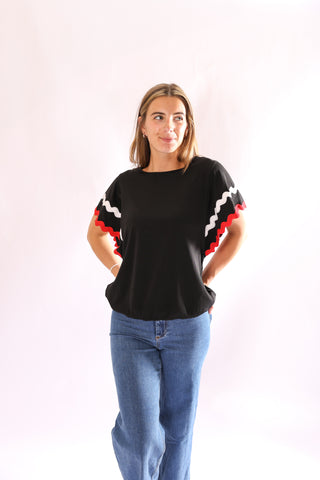 Woman wearing black Ziggy Shirt with red and white wavy trim sleeves and elastic hem