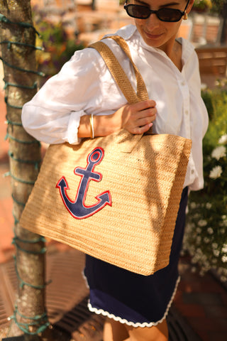 Woman wearing the Clementine Skort in navy blue with white rickrack trim, styled with sandals and a white blouse and a woven bag with an anchor.