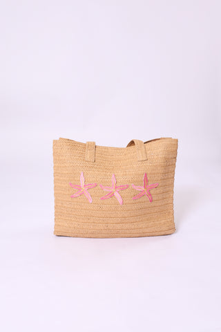 Palma Tote Bag crafted from natural paper straw, featuring three embroidered pink starfish across the front.