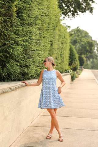 Woman wearing Sophia Dress in Blue Floral print, sleeveless A-line silhouette with pockets.
