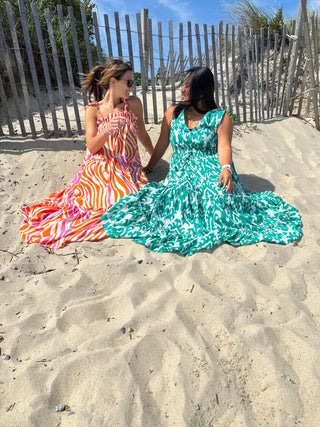 Pink and Orange Ripple strappy tiered maxi dress, on model sitting on beach