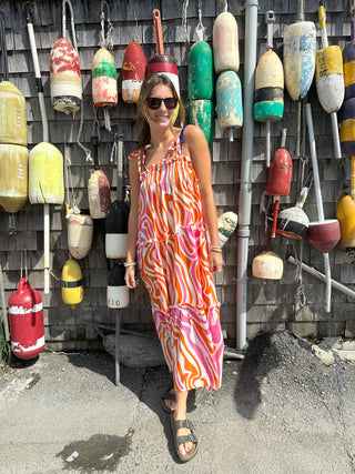 Pink and Orange Ripple strappy tiered maxi dress, on model standing near buoys 