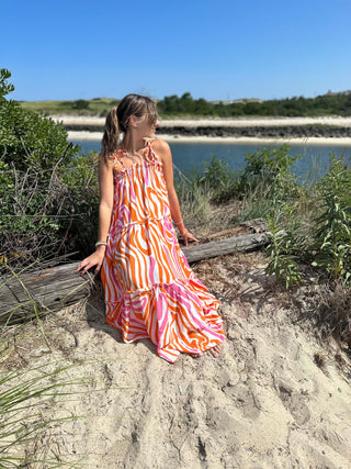 Pink and Orange Ripple strappy tiered maxi dress, on model sitting at beach