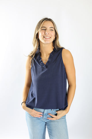 Model in navy Sunny Top sleeveless blouse with ruffle neckline and jeans