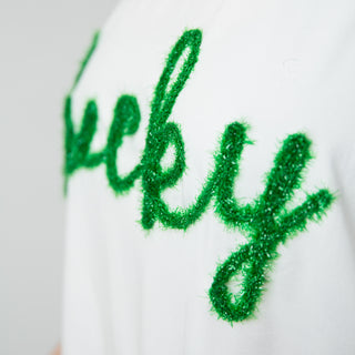 Elbow-sleeved crewneck shirt with the word lucky written in green garland on front, close up view of letters