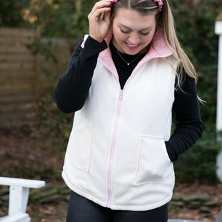 Light pink reversible vest with zipper and pockets while reversed. Reversed vest is white with pink zipper and collar