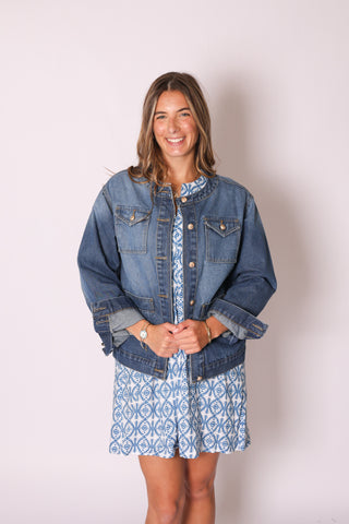 Woman wearing Coco Jean Jacket in light wash denim, styled over a blue printed dress.