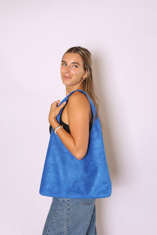 Woman holding a blue tote bag against a white background