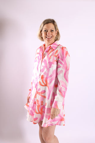 Woman wearing the Dottie Dress in pink coral reef print, long sleeves, drop waist design.