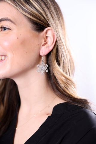 woman wearing hanging silver snowflake earrings