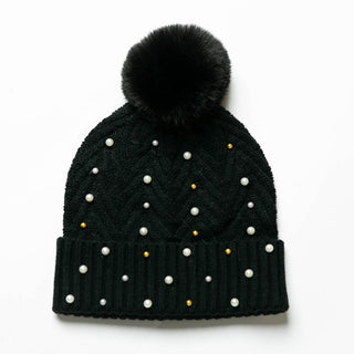 Black knit hat with pom-pom decorated with pearls and gold balls.