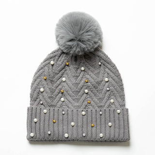 Gray knit hat with pom-pom decorated with pearls and gold balls.