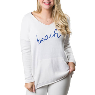 White sweater with front kangaroo pocket and beach written in blue
