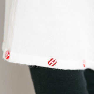 close up of white poncho with peppermint candy button trim